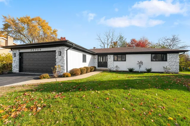 a front view of house with yard and trees in the background