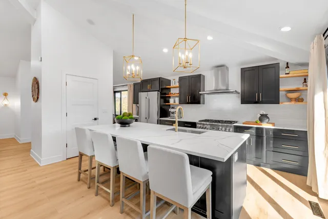 a kitchen with kitchen island a dining table chairs and white appliances