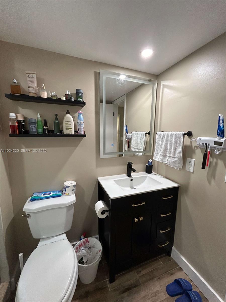 8977 Wiles Road, Unit 208 Coral Springs, FL 33067 - Photo 11 of 28 a bathroom with a toilet sink and mirror