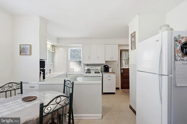 a kitchen with a refrigerator a stove a sink and chairs
