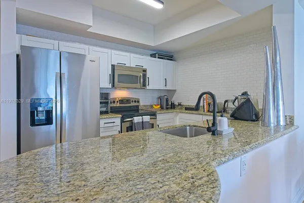 a kitchen with granite countertop a refrigerator and a sink