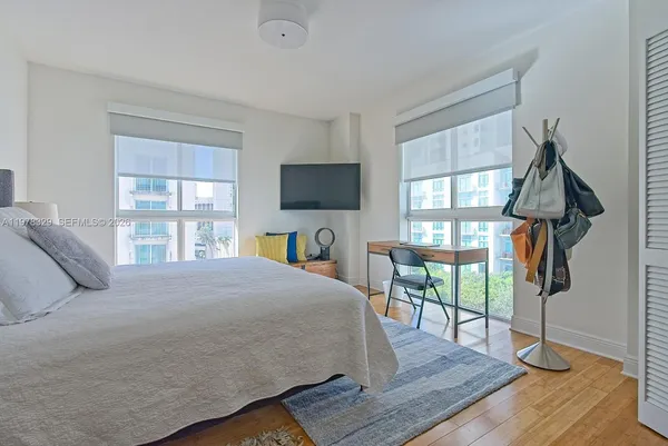 a bedroom with a bed a flat screen tv and a book shelf