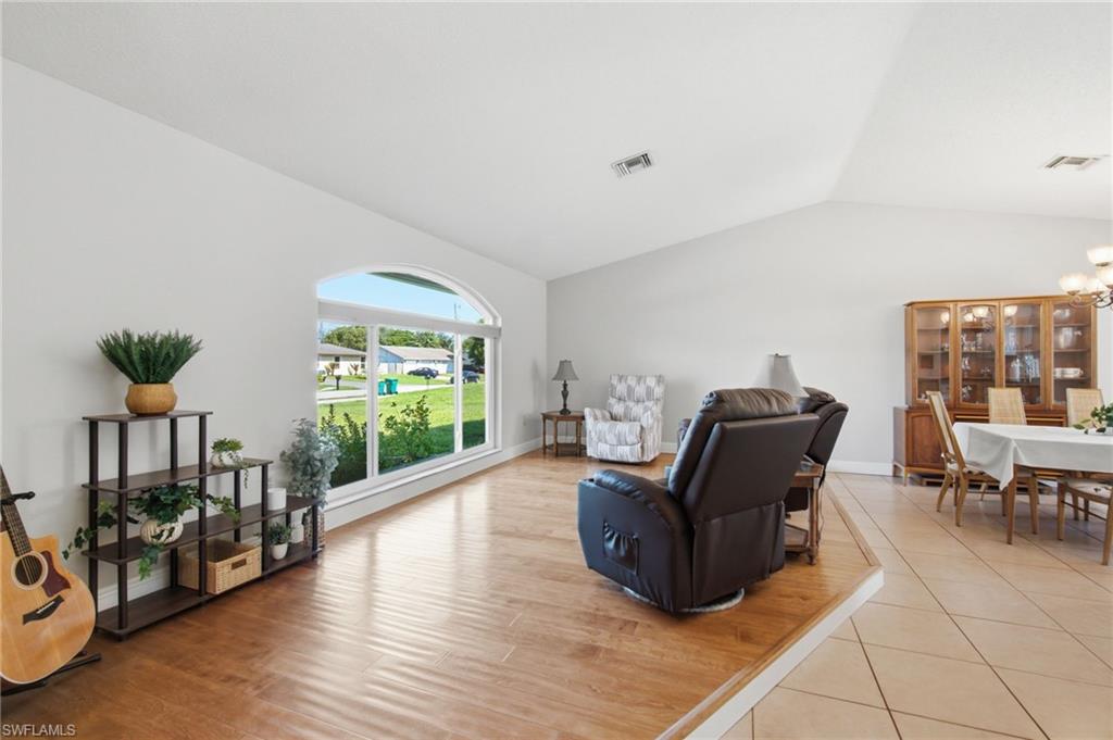 3022 47th Street Southwest Naples, FL 34116 - Photo 6 of 46 Living area featuring vaulted ceilings, wood-finish flooring, and an arched picture window