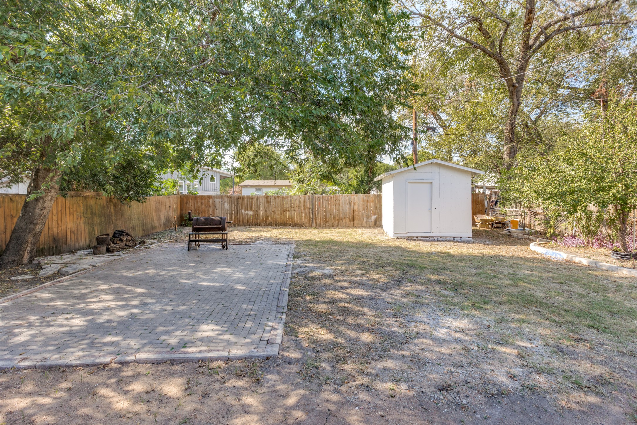 1118 Spur Street Austin, TX 78721 - Photo 13 of 21 A versatile backyard features a paved patio and a detached storage shed, perfect for outdoor living.
