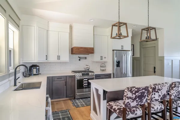 a kitchen with stainless steel appliances a sink a stove a refrigerator cabinets and living room view