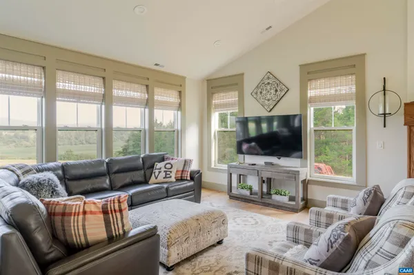a living room with furniture flat screen tv and a large window