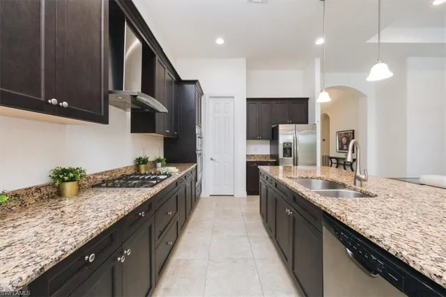 a kitchen with stainless steel appliances granite countertop a stove a sink a refrigerator and chairs
