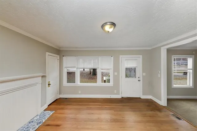 a view of an empty room with window and wooden floor