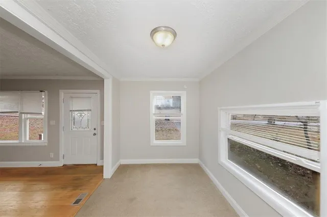 a view of an empty room with wooden floor and window