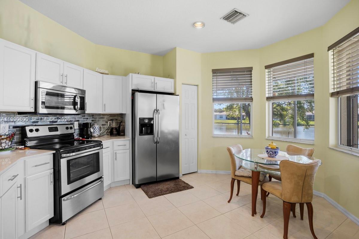 337 Southwest Maclay Way Port St. Lucie, FL 34986 - Photo 10 of 44 a kitchen with stainless steel appliances a stove a sink refrigerator and a dining table
