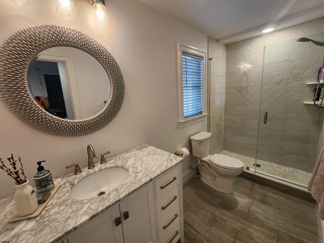a bathroom with a granite countertop sink mirror vanity and toilet