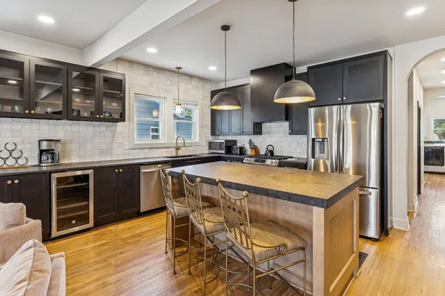 a kitchen with stainless steel appliances granite countertop a sink a stove a refrigerator cabinets and wooden floor