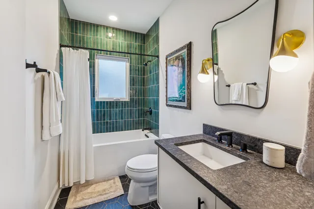 a bathroom with a granite countertop sink a toilet and shower