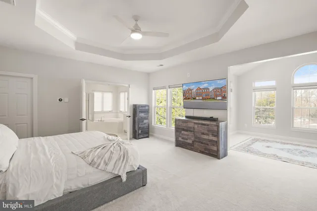 a spacious bedroom with a bed a chandelier and a mirror