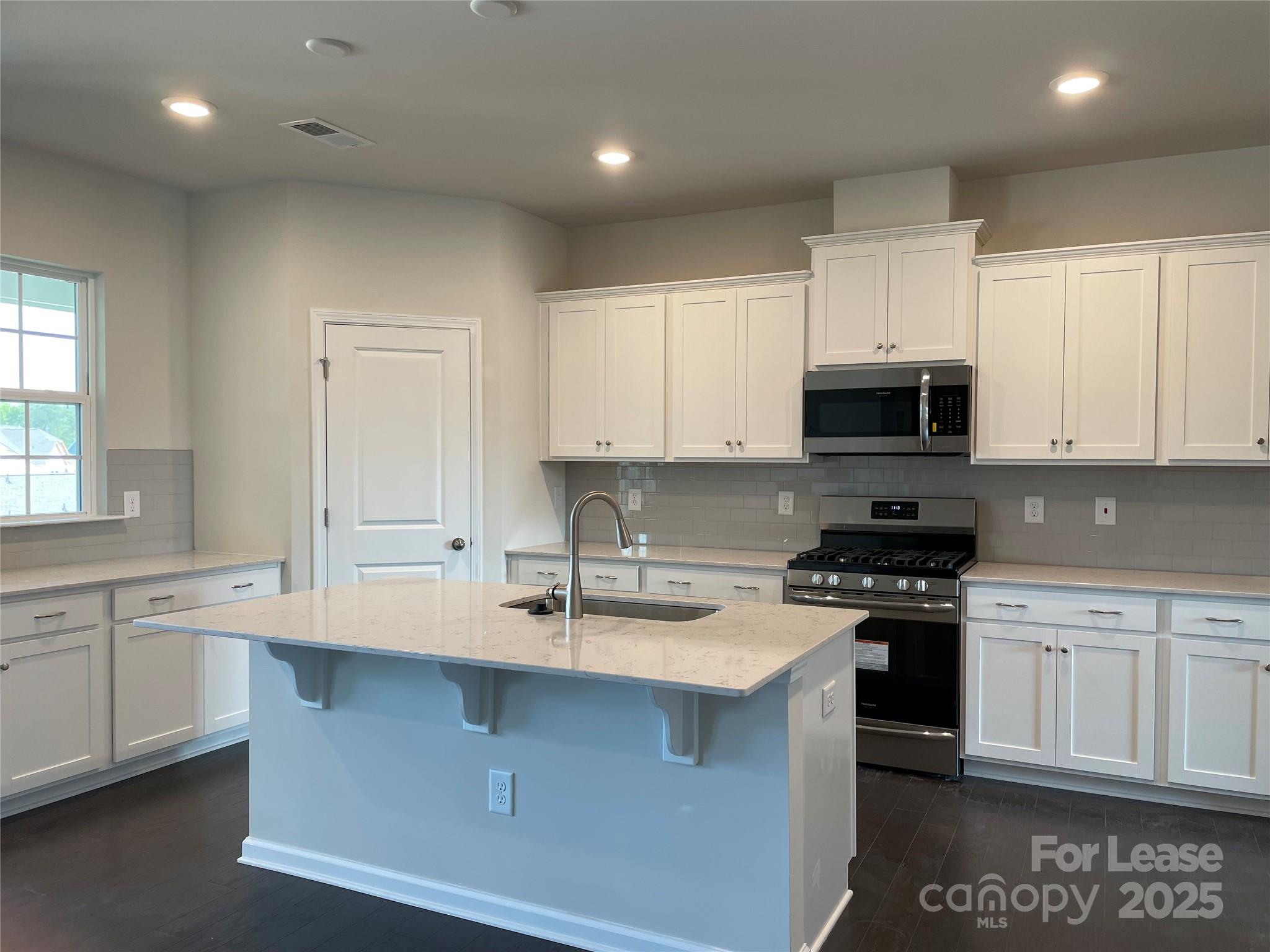 17618 Snug Harbor Road, Unit LOT75 Charlotte, NC 28278 - Photo 3 of 33 a kitchen with kitchen island granite countertop white cabinets stainless steel appliances and a sink