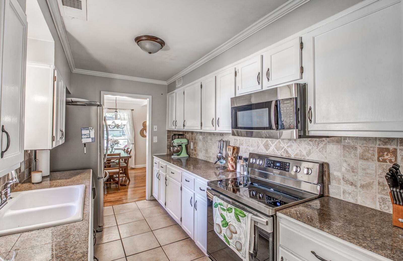 1377 Marcia Road Memphis, TN 38117 - Photo 9 of 24 a kitchen with stainless steel appliances granite countertop a stove a sink and a microwave