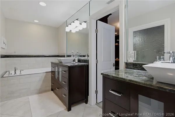 a bathroom with a granite countertop sink a mirror a bathtub and shower