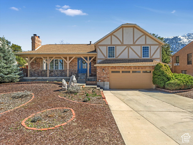 10299 South 2505th Street East Sandy, UT 84092 - Photo 1 of 1 Tudor home featuring roof with shingles, an attached garage, driveway, a porch, and a chimney