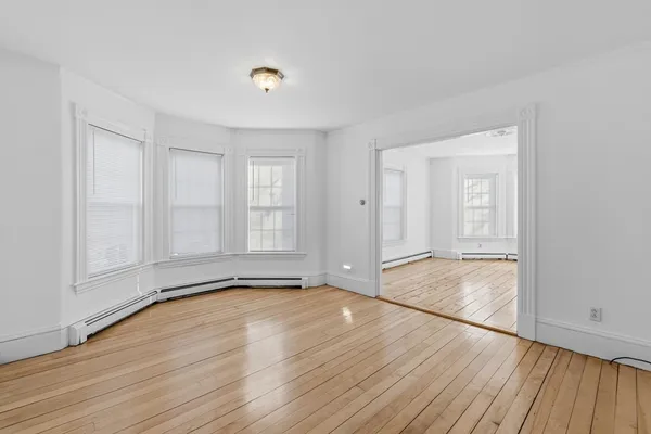 a view of an empty room with wooden floor and a window