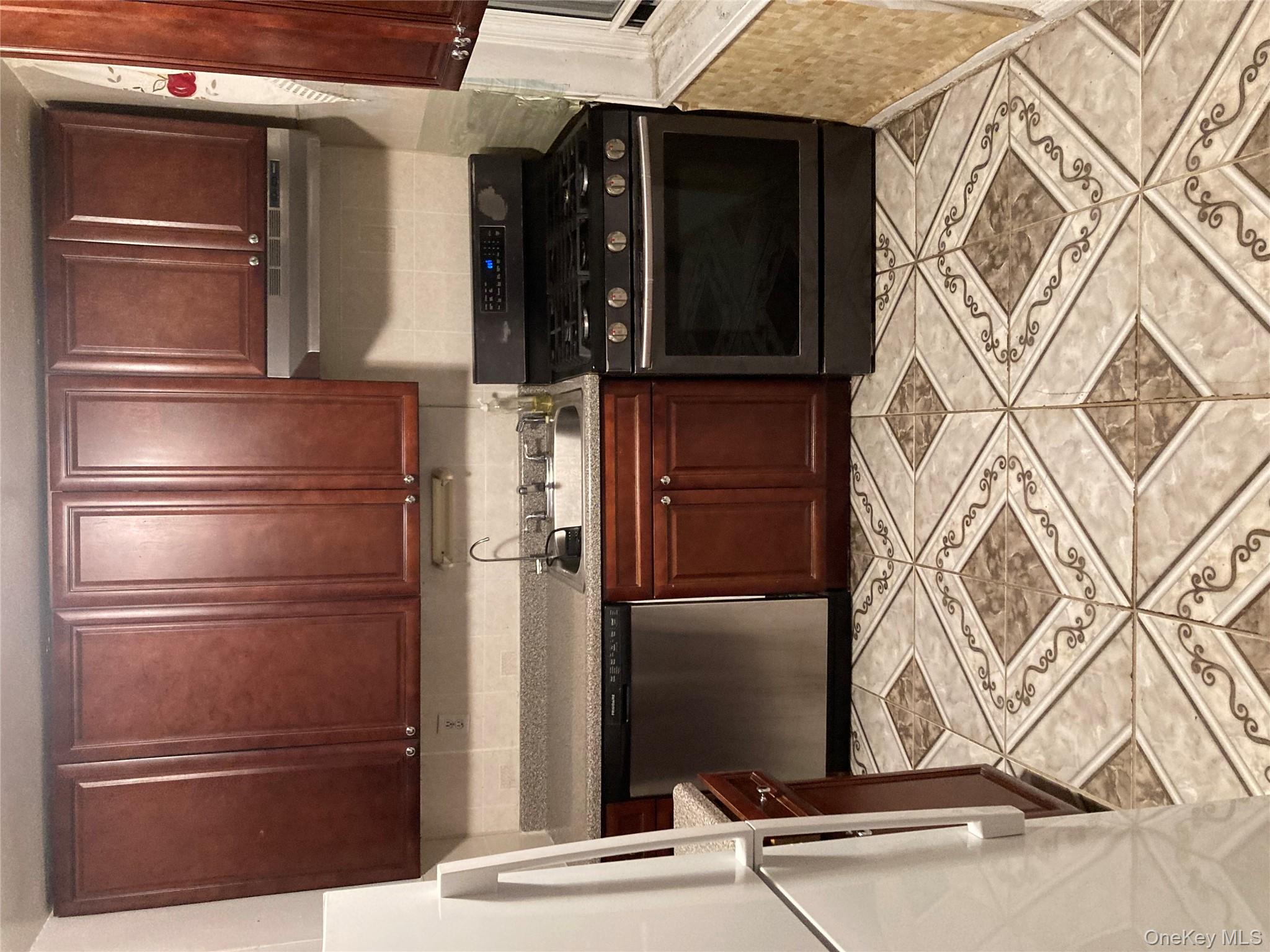 62-59 108th Street, Unit 6E Queens, NY 11375 - Photo 8 of 14 a kitchen with granite countertop wood cabinets and stainless steel appliances