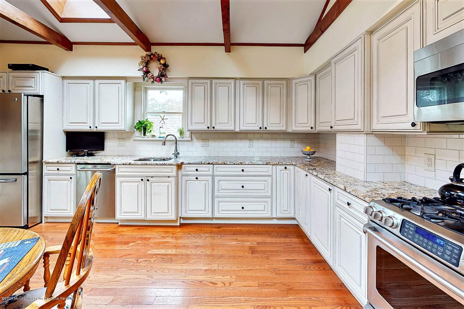 54 Ridge Avenue Manasquan, NJ 08736 - Photo 14 of 42 a kitchen with stainless steel appliances granite countertop a stove a sink dishwasher and white cabinets with wooden floor