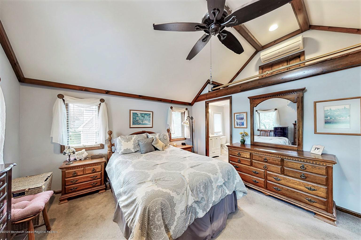 54 Ridge Avenue Manasquan, NJ 08736 - Photo 22 of 42 a bedroom with a bed a chandelier and flat screen tv
