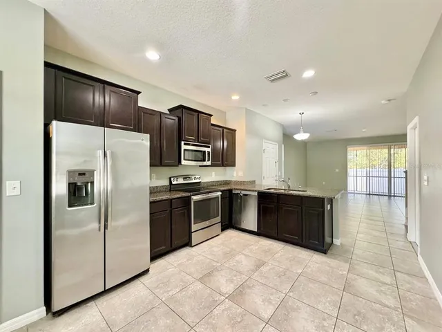 a large kitchen with a large counter top stainless steel appliances and cabinets