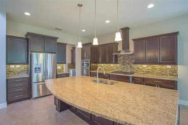 a kitchen with stainless steel appliances granite countertop a sink and a refrigerator