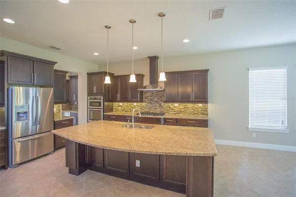 a large kitchen with kitchen island a large counter top stainless steel appliances and cabinets
