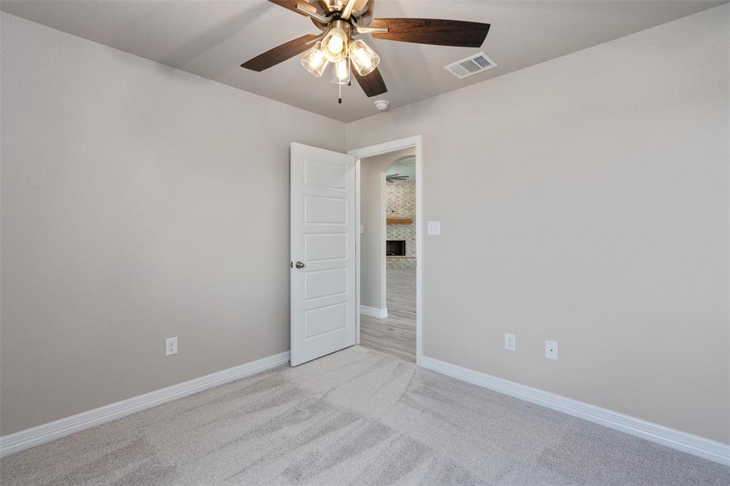 1341 Promised Land Road Hewitt, TX 76643 - Photo 20 of 29 Carpeted room featuring a ceiling fan with light fixture, light gray walls, white trim, and a five-panel interior door