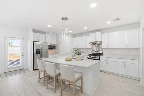 a kitchen with a sink a refrigerator and white cabinets