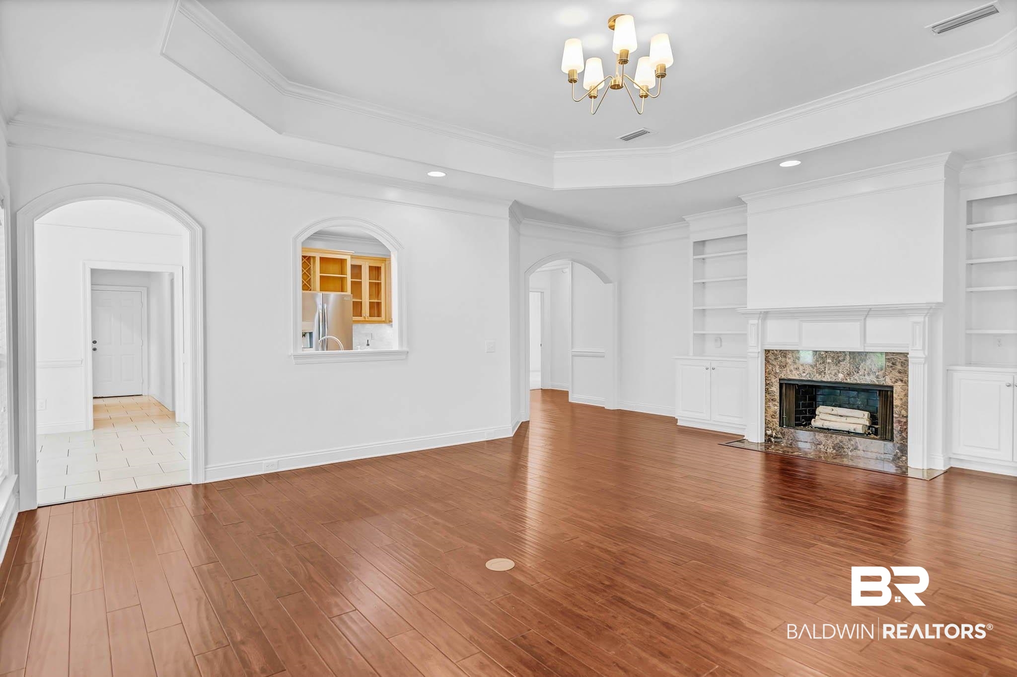 105 Cedar Pointe Fairhope, AL 36532 - Photo 11 of 38 Unfurnished living room with ornamental molding, arched walkways, wood finished floors, a raised ceiling, and a fireplace