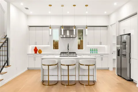 a kitchen with stainless steel appliances kitchen island granite countertop a refrigerator and a stove top oven with white cabinets