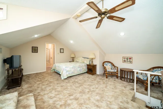 a spacious bedroom with a bed a chandelier and flat screen tv