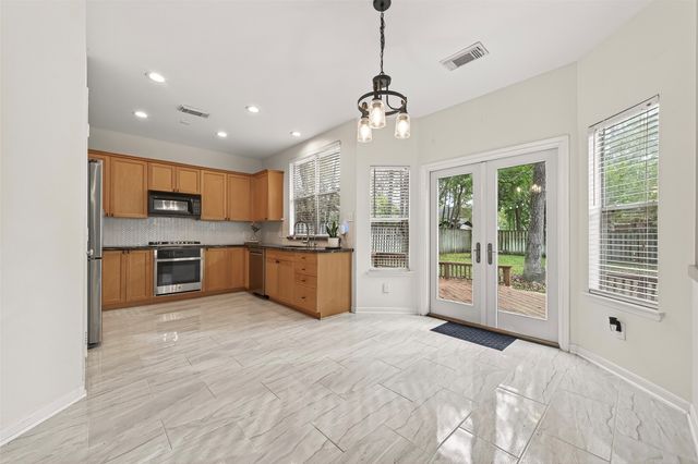 a large kitchen with kitchen island a large window and stainless steel appliances