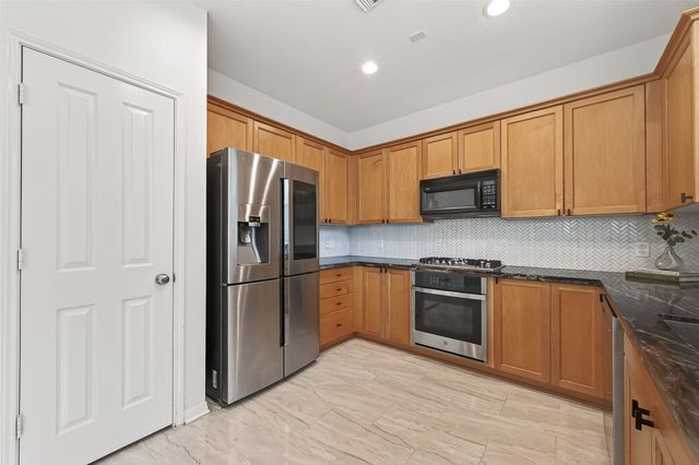a kitchen with stainless steel appliances granite countertop a refrigerator stove and sink