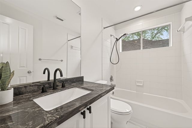 a bathroom with a granite countertop sink a toilet and a bathtub