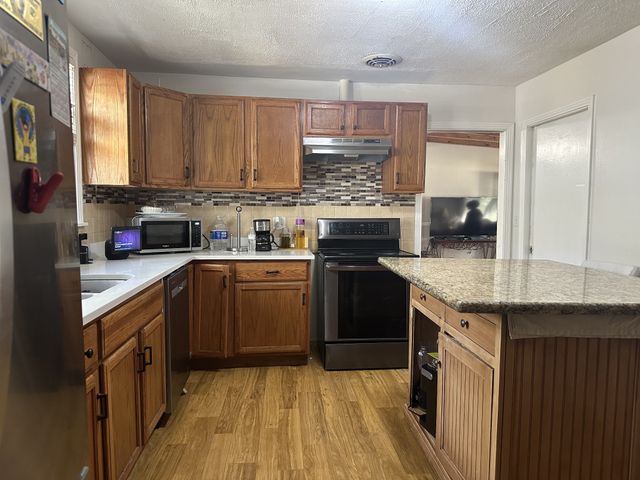 a kitchen with kitchen island granite countertop a sink cabinets and stainless steel appliances