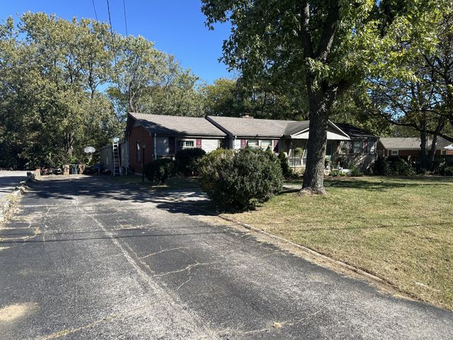 a view of a house with a yard and large tree