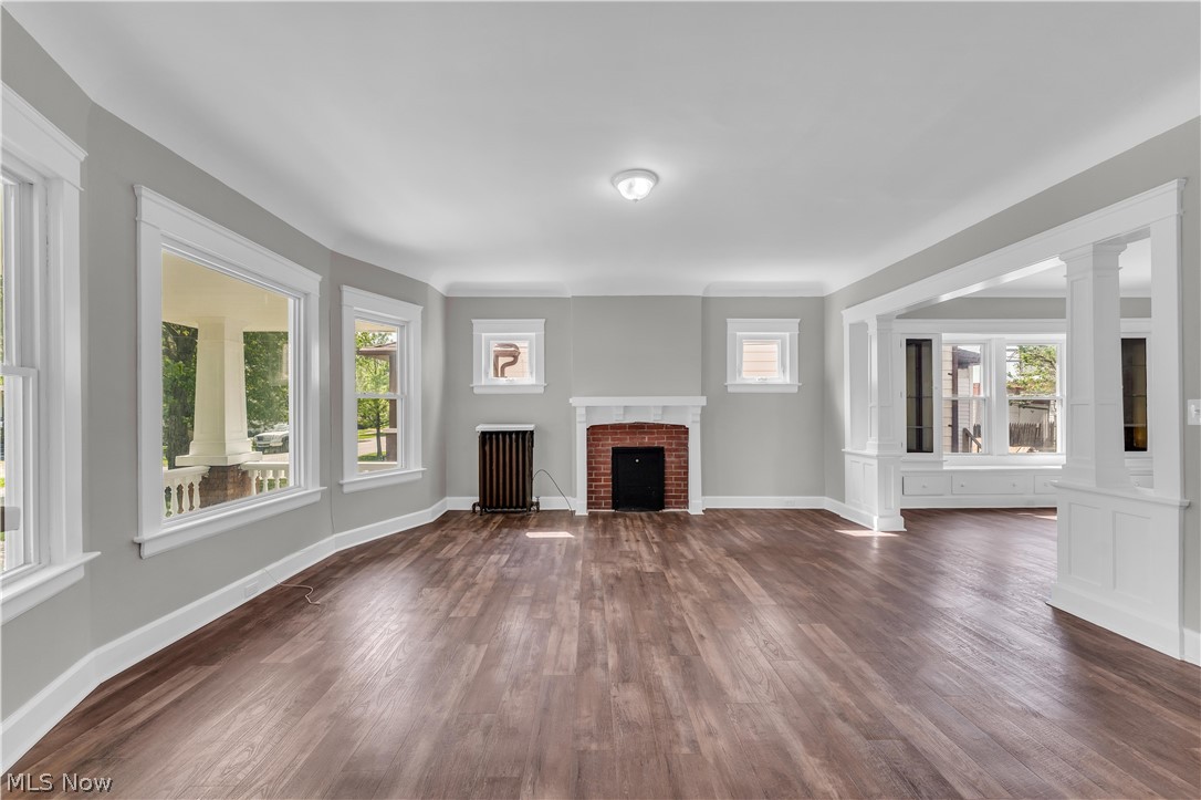 3506 Riverside Avenue Cleveland, OH 44109 - Photo 5 of 31 Spacious living area featuring wood-finish flooring, a brick fireplace with a white mantel, and ample natural light from multiple windows