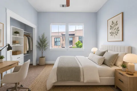 a bedroom with a bed a couch and large window
