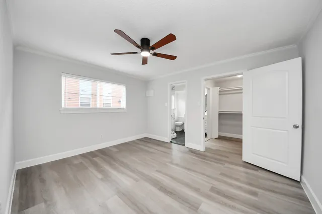 a view of empty room with wooden floor and fan