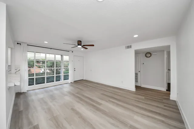 a view of empty room with wooden floor and fan