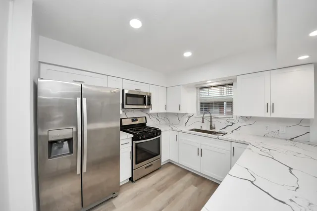 a kitchen with stainless steel appliances granite countertop a sink stove and refrigerator