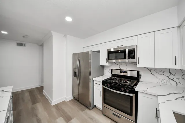 a kitchen with stainless steel appliances a stove a microwave and white cabinets