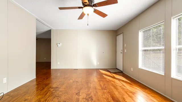 a view of an empty room with window and a chandelier fan