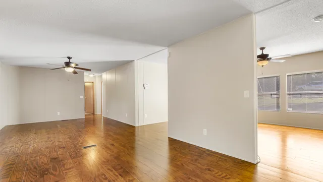 an empty room with wooden floor and windows