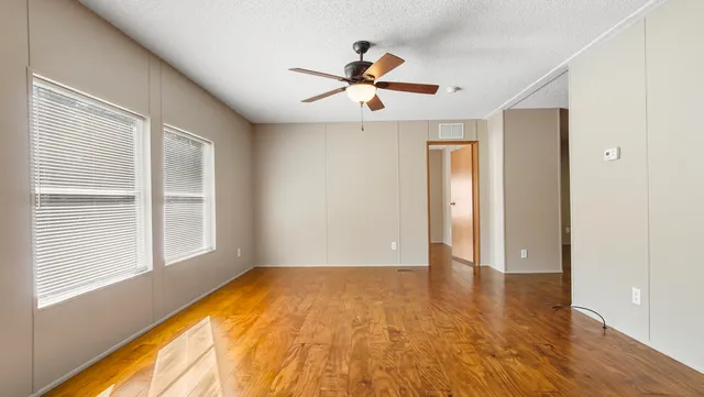 a view of empty room with wooden floor and fan