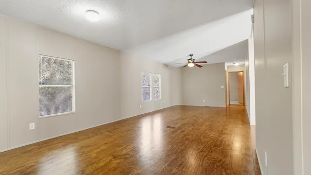 a view of empty room with wooden floor and fan