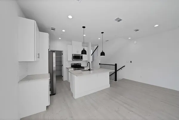 a large white kitchen with a sink stainless steel appliances and cabinets